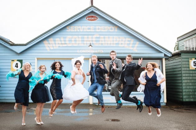 Bridal party jump outside the Malcolm Campbell service depot at Brooklands Museum, Weybridge