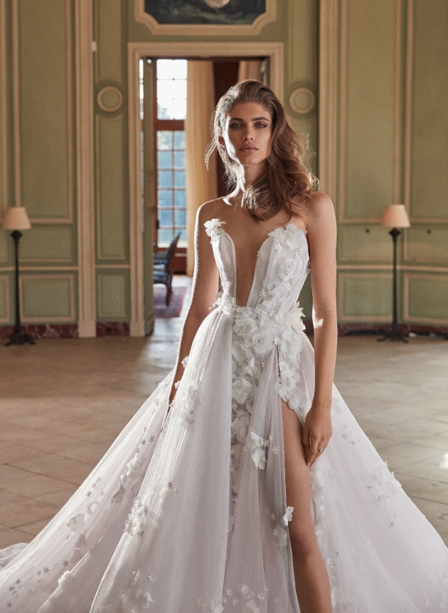 Model is standing in a manor house and is wearing a wedding dress with 3D petals