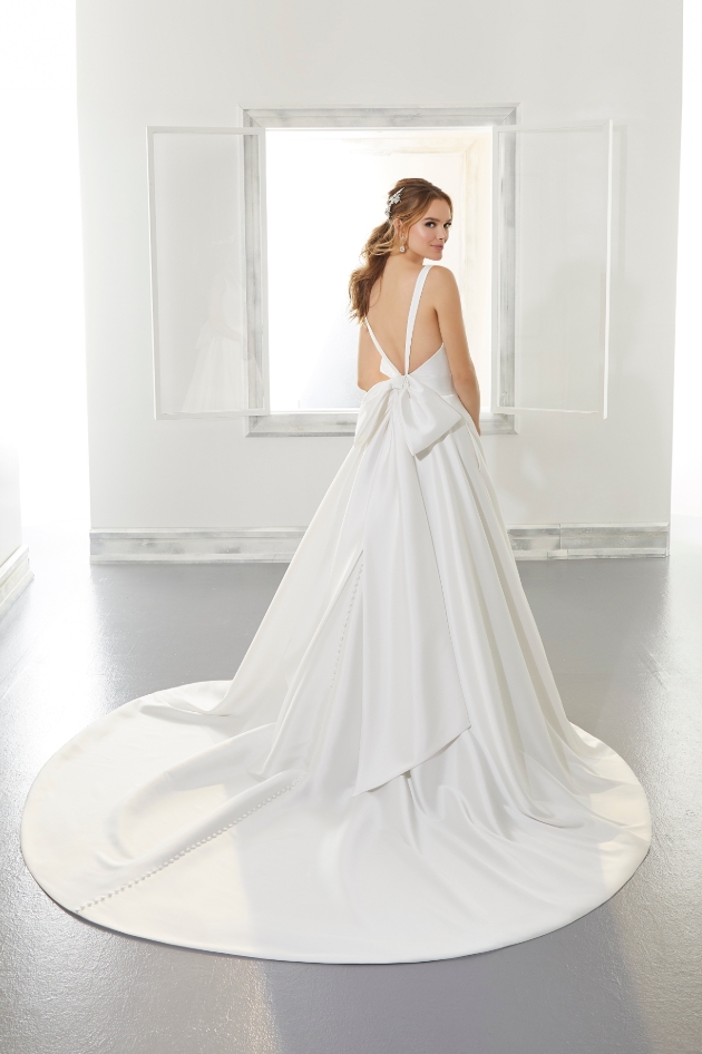 Plunge back strap wedding dress worn by model and features bow