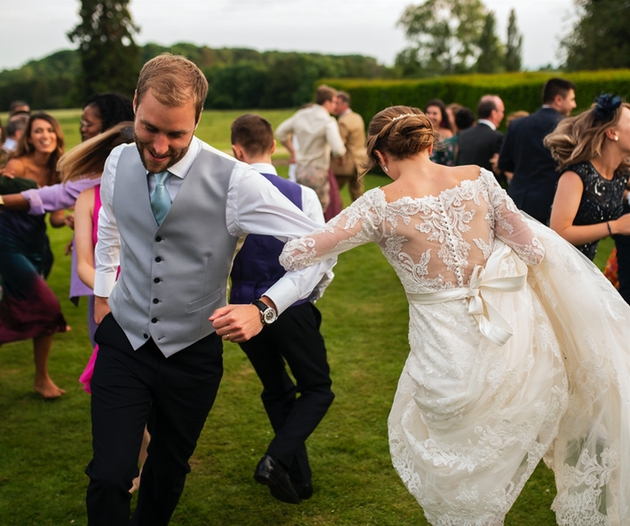 Couple performing a ceilidh on wedding day surrounded by guests