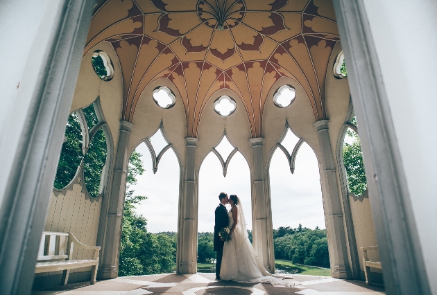 Couple kiss under the white Gothic temple at Painshill in Surrey featured in Bridgerton