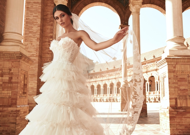 model wearing strapless ruffled gown with ruins in the background