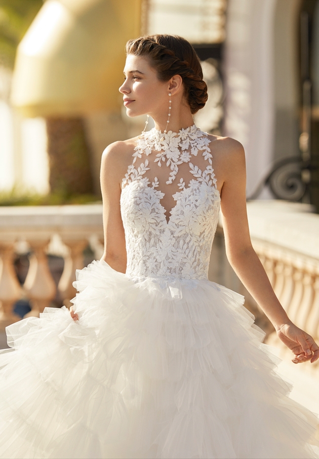 model wearing gown with ruffle skirt and high lace neckline