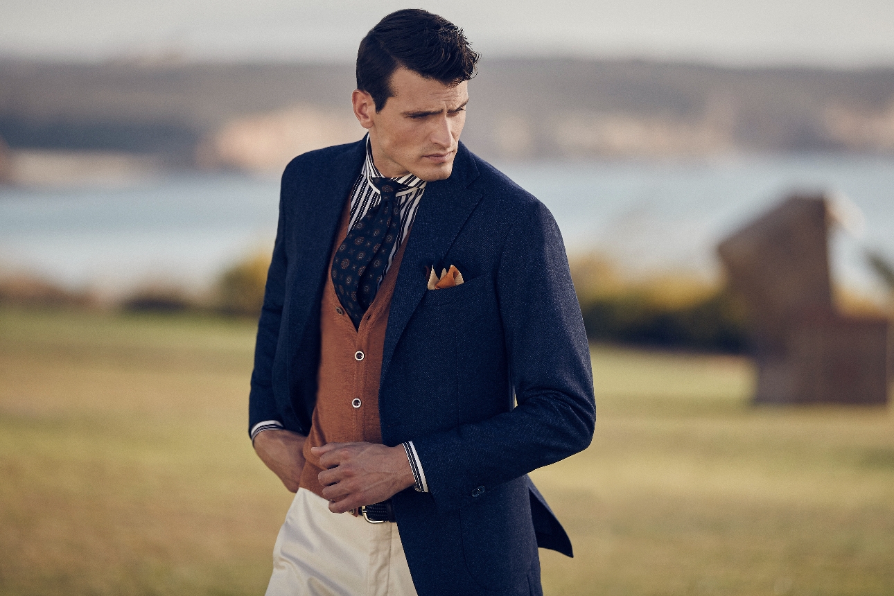 man in country style formal attire walking through field