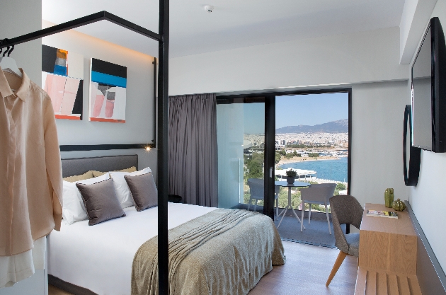 bedroom with white walls, a bed, and views of the sea