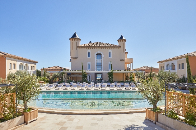 Hotel with turrets, overlooking a pool with sun loungers surrounding it