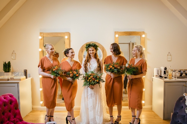 a bride and her bridesmaids standing in a room holding big floral bouquets 