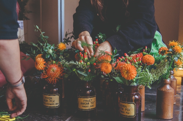 a florist organising flowers in small jars on a table