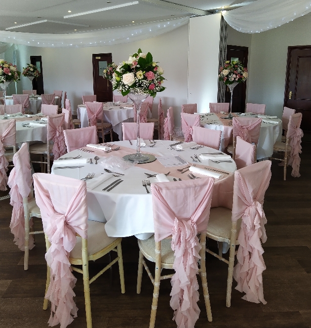 wedding reception room with tables set up for seated dinning, with tall flower arrangements in the center