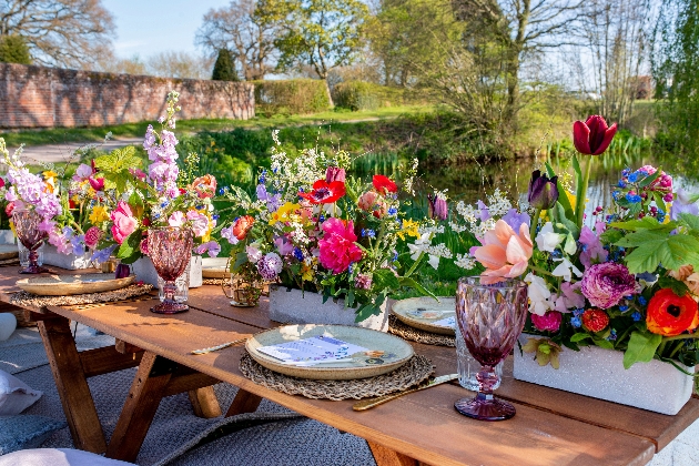 trestle tables outdoors filled with flowers and crockery