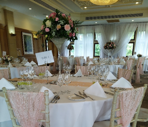 reception table with white cloth and a martin vase of flowers 