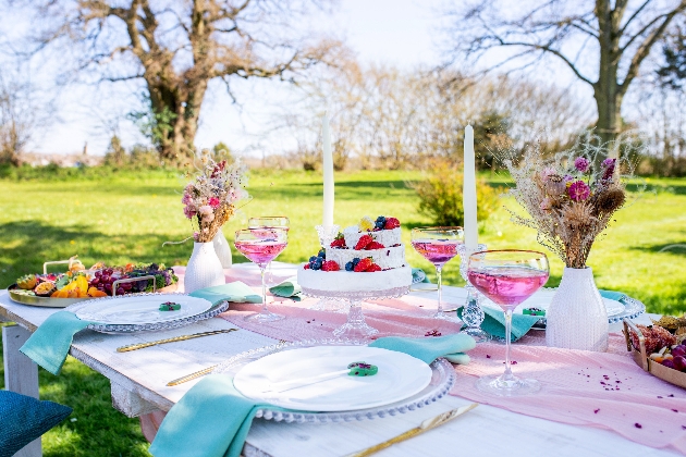 outdoor table with cake, flowers, and dinning ware 