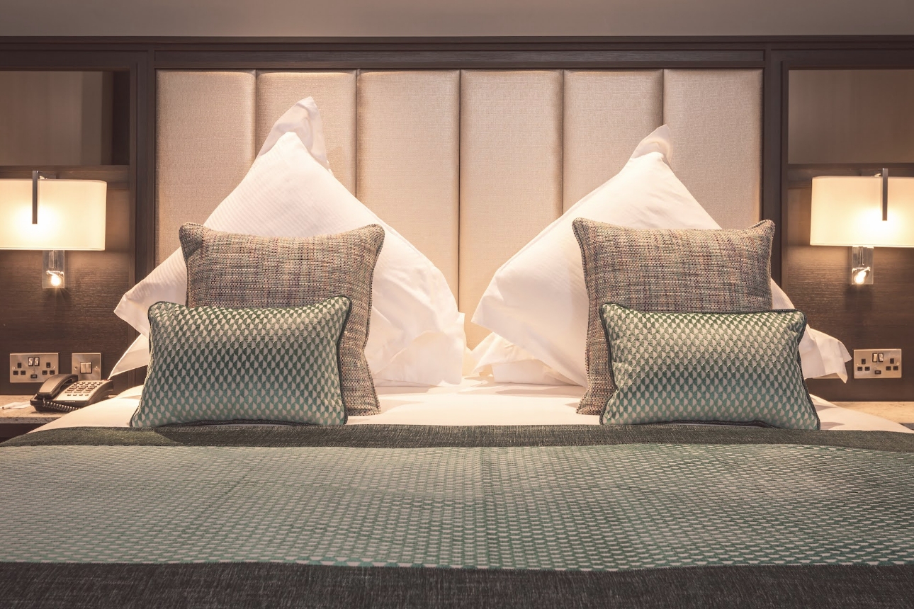 Modern hotel bed with white linen and tall headboard