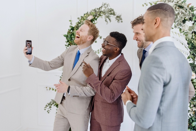 wedding guests and groom l looking at a mobile phone