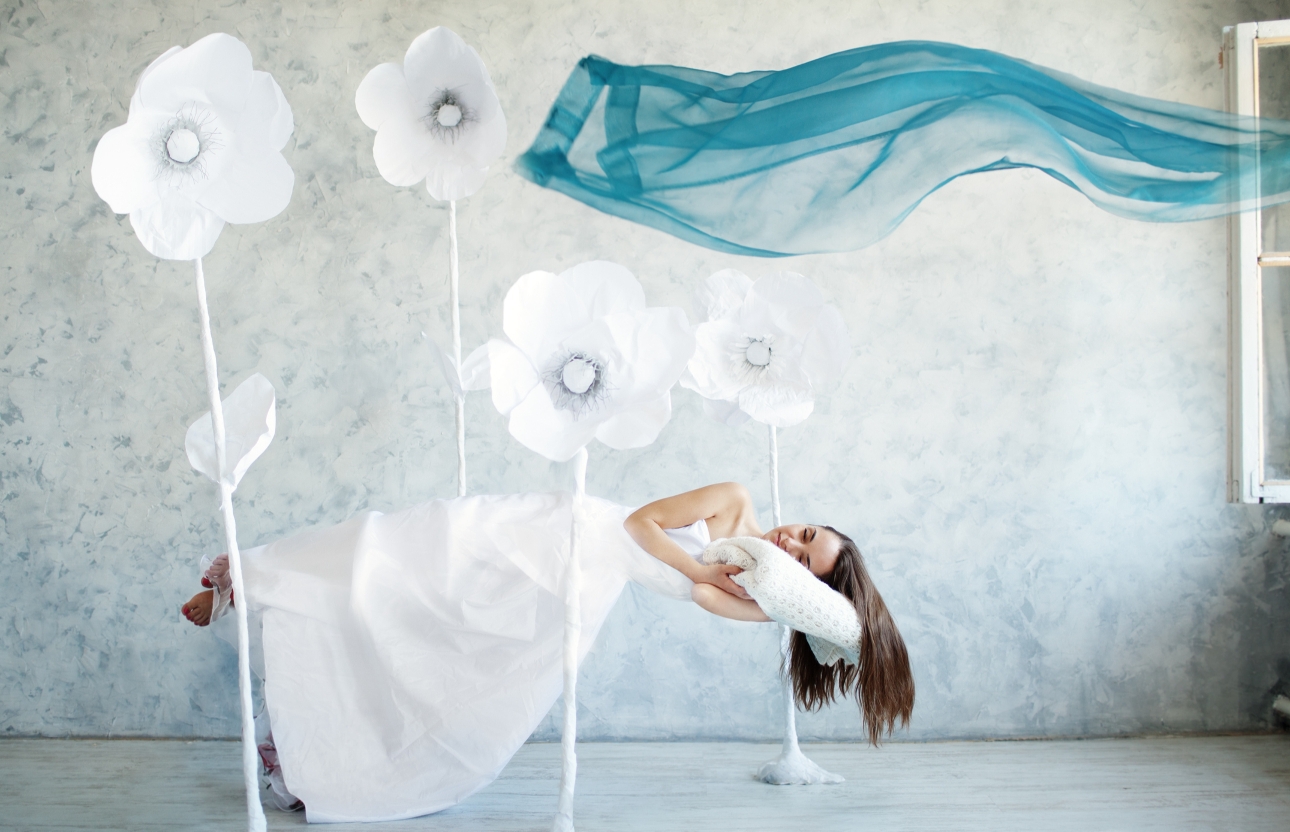 woman in a wedding dress laying down happily dreaming on a pillow