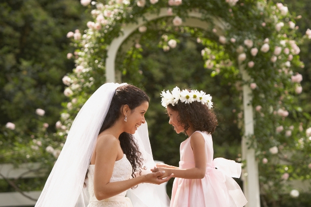 bride bent down holding hands with bridesmaids with daisy crown