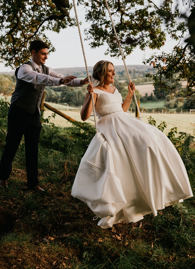 Groom pushing bride on swing