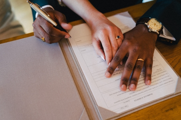 Couple's hands while they sign the wedding register