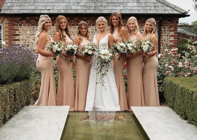 A bride standing in the middle of her six bridesmaids