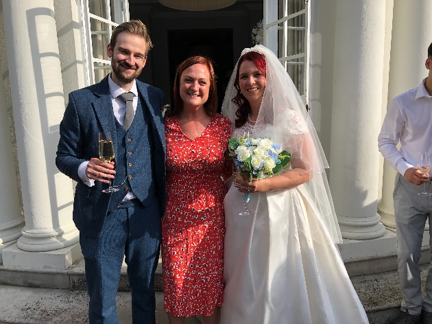 Teri Burvill standing next to a happy bride and groom