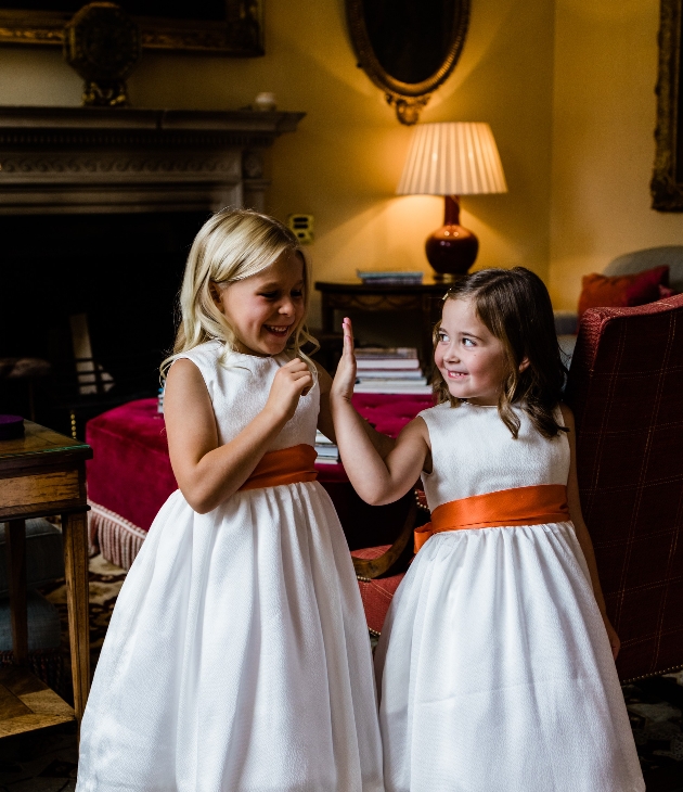 two flowergirl in white dresses with orange sashes