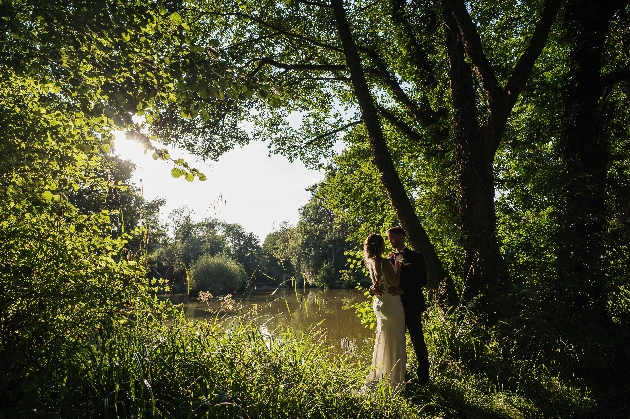 Bride and groom embracing near a pond