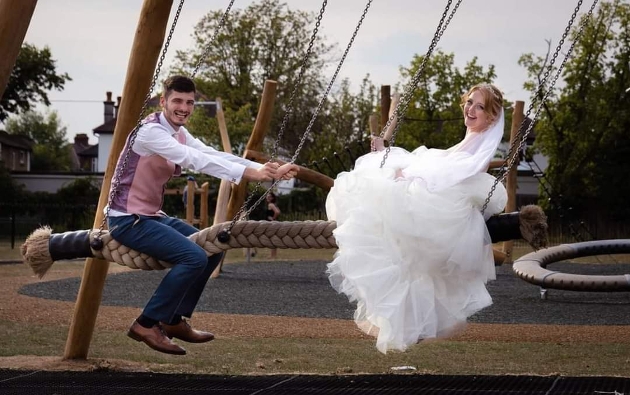 bride and groom on a play park swing ride