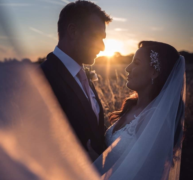 bride and groom at sunset, veil in foreground