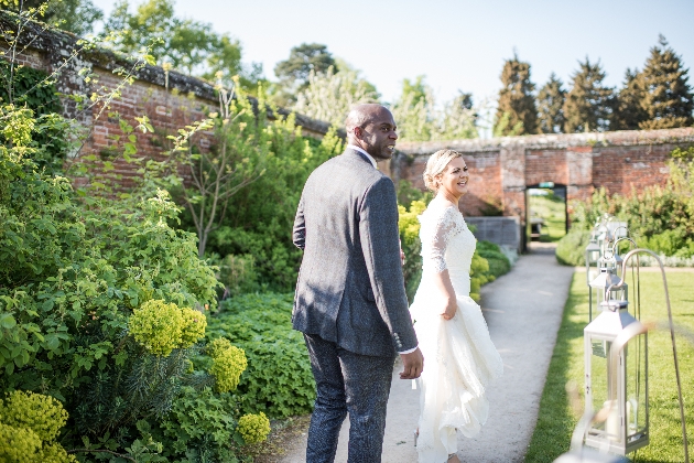 couple walking through a walled garden in their wedding attire
