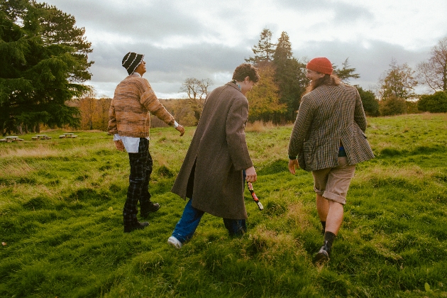 three people walking through grass land