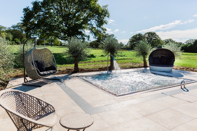 jacuzzi in middle of paved area, seating snugs grounds around it