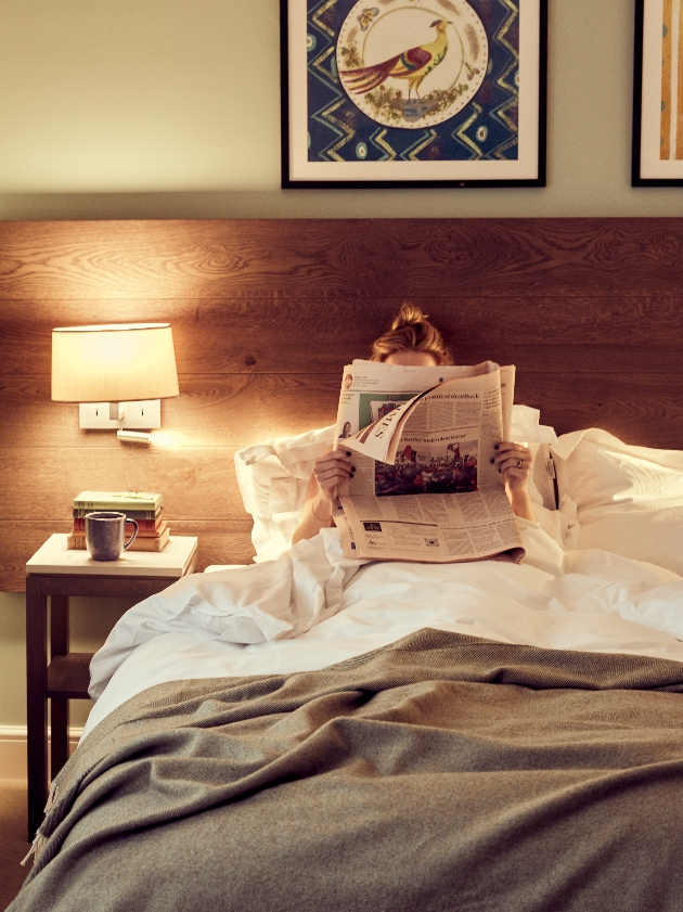 woman in bed reading paper