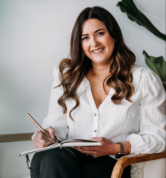 head shot of Nicci sat in chair holding book