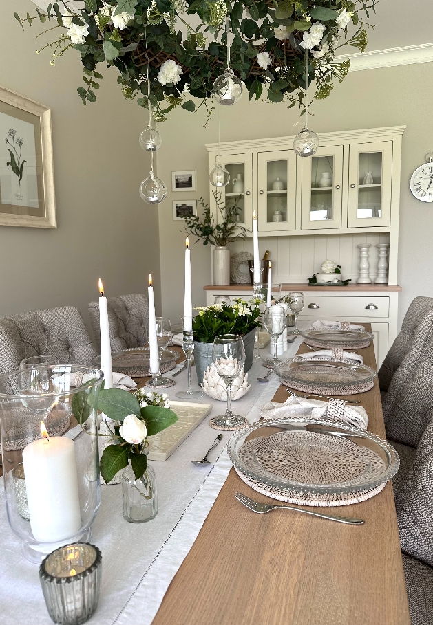 table set up for dinner, floral decoration hanging, white plates and clear glassware