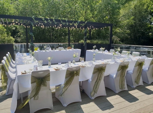 outdoor tables, in two l-shape layouts wooden gazebo above with lights