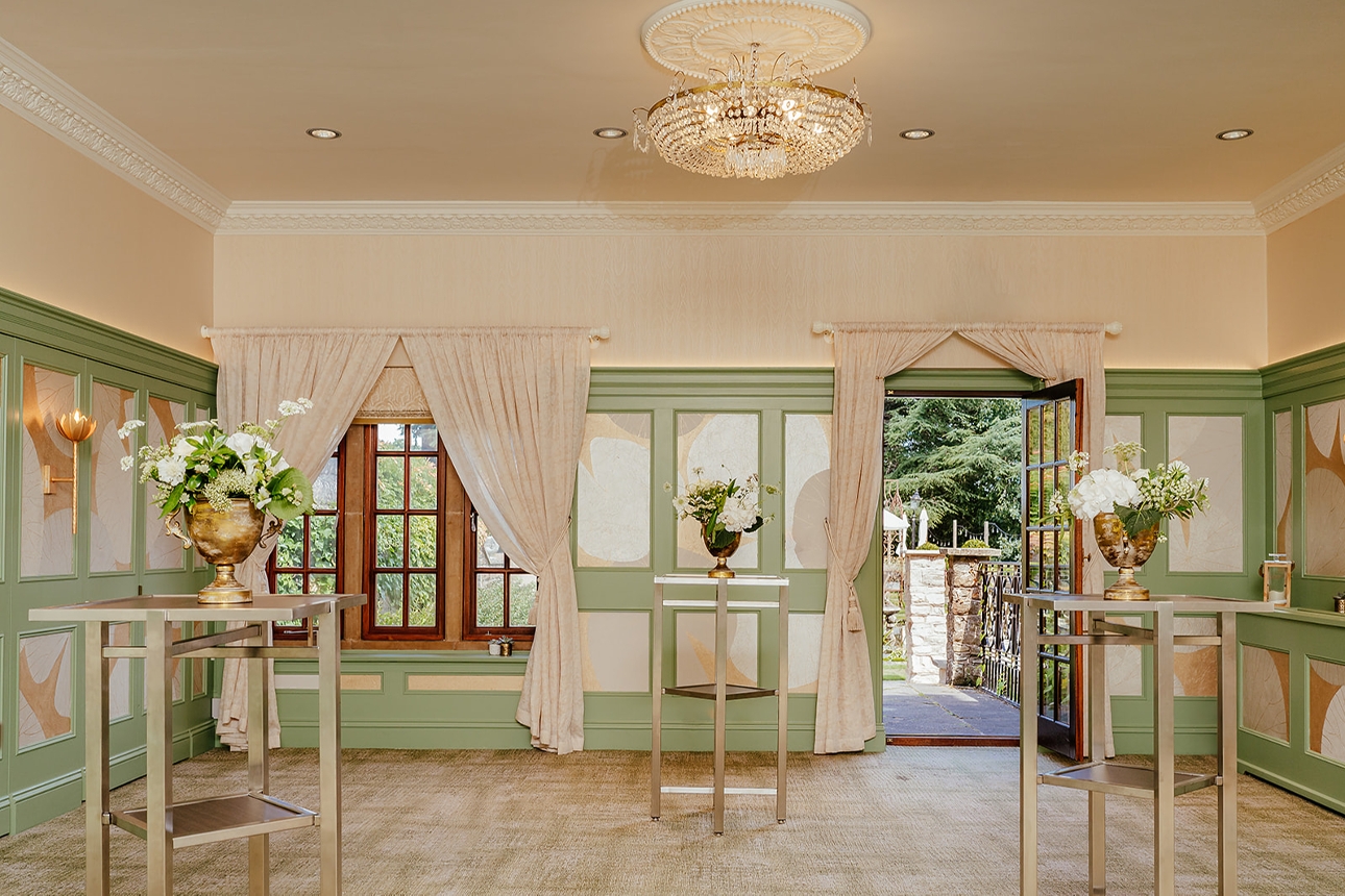 room with cream and green colour palette chandelier on ceiling high conference tables