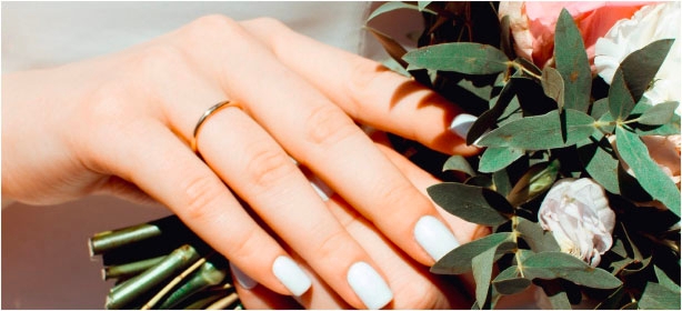 hand holding flowers and wearing wedding band 