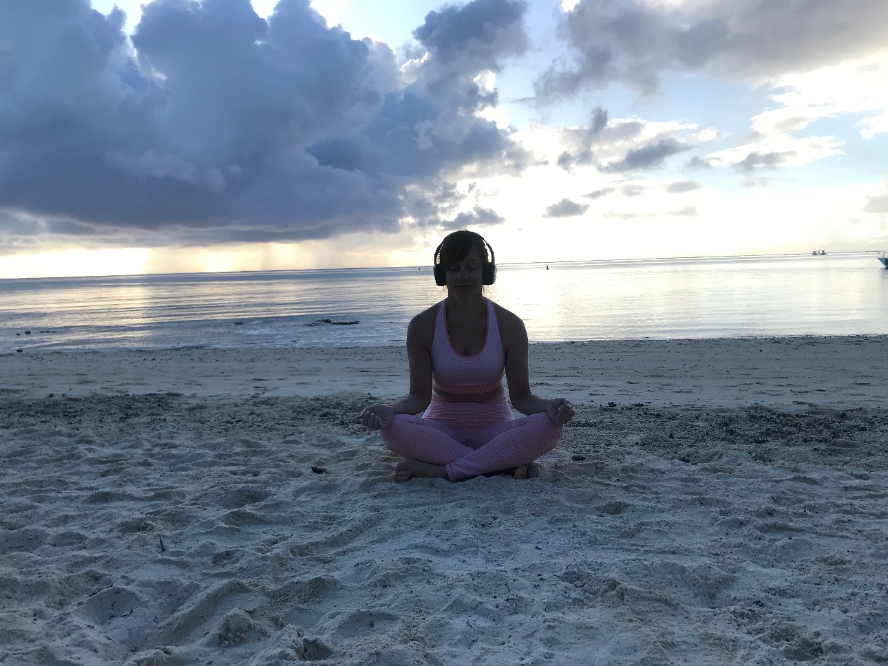 claire sat on beach with headphones on meditation