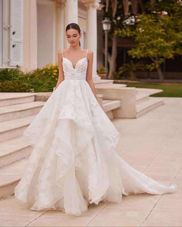 model in waterfall tiered gown with thin straps and floral details