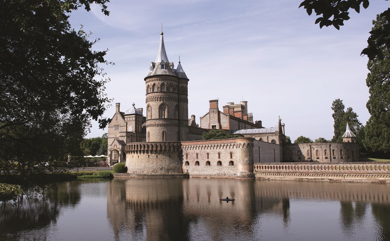 fairytale style tower surrounded by turret and moat and pond