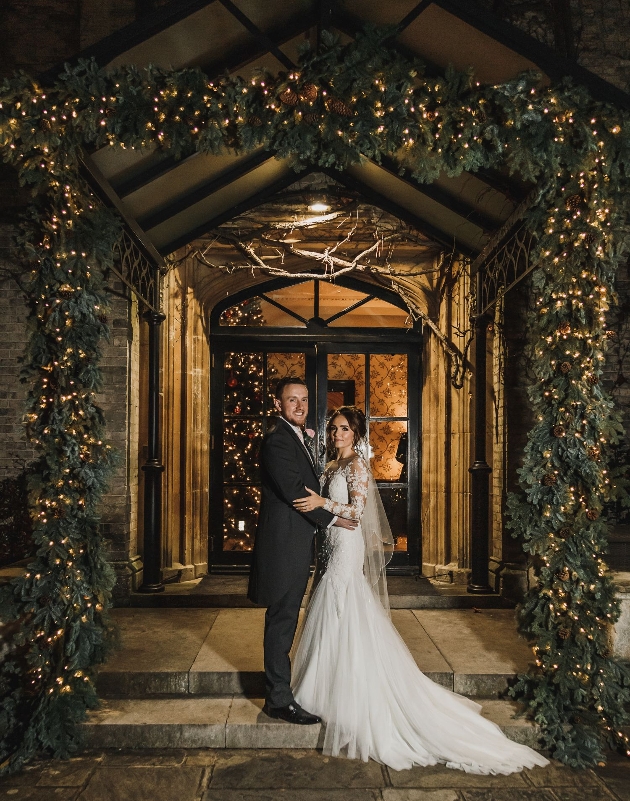 couple in door way with festive arch above them 