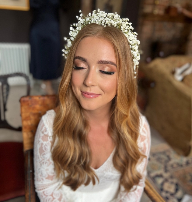 Bride with her eyes closed showing off her eye makeup wearing a gypsophila flower crown 