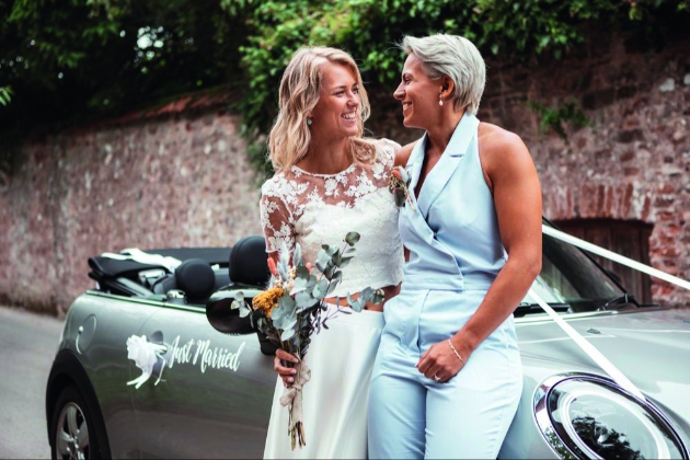 Brides leaning on a car wearing glowing fake tans
