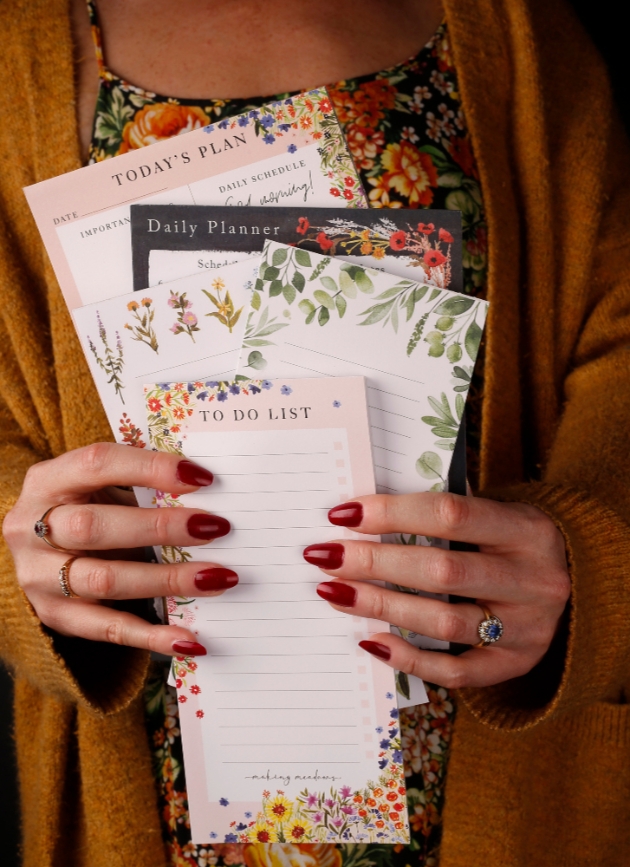 Woman with red nails holding a bunch of to do list pads by Making meadows