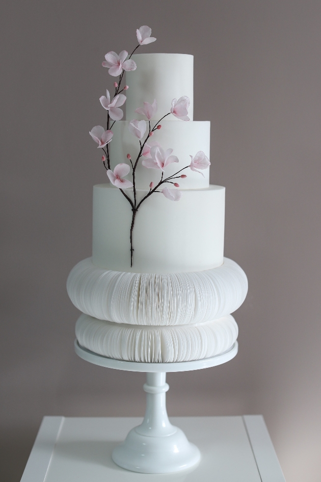 white three tier wedding cake with cherry blossom branch decorating it