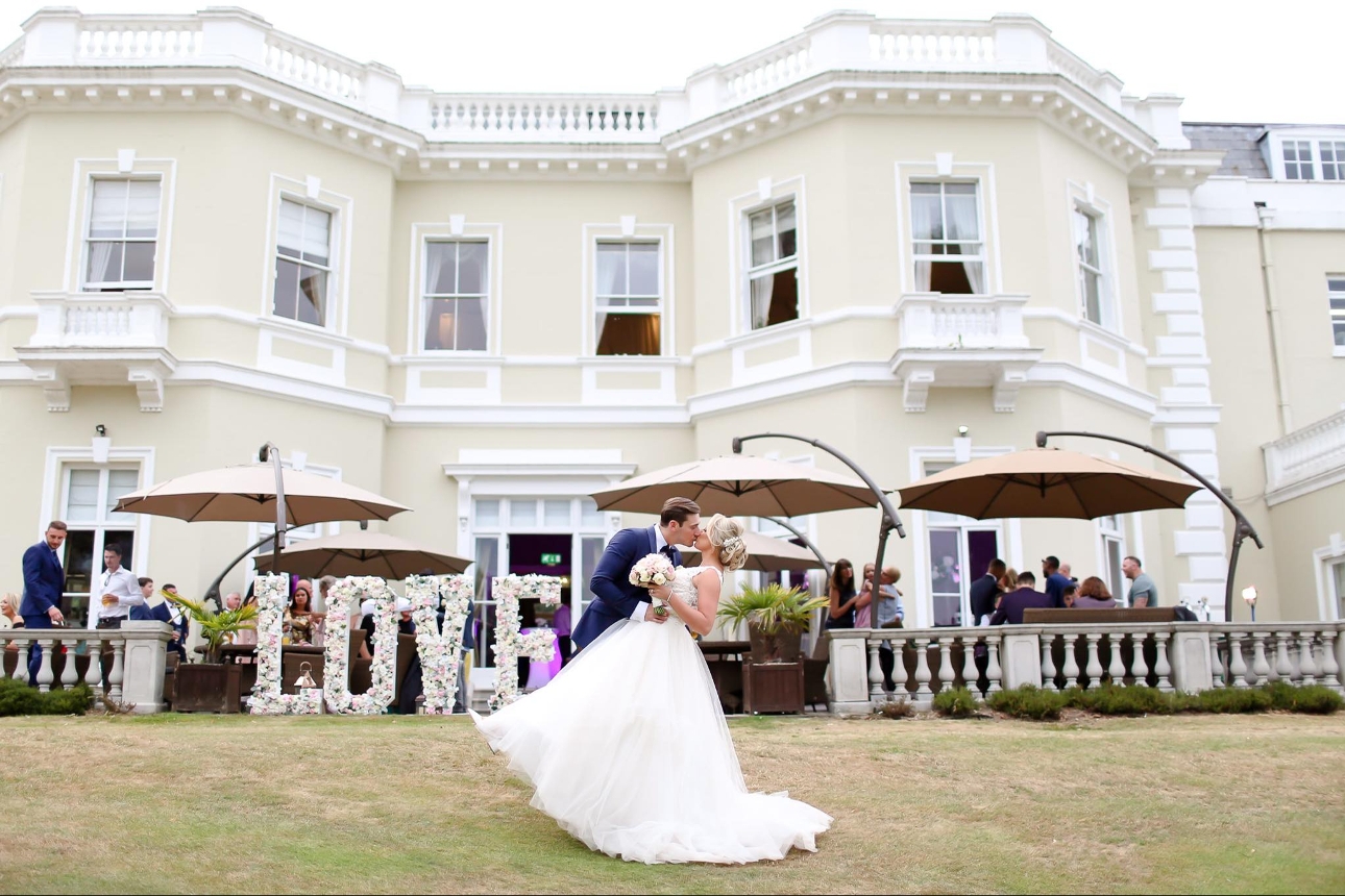 Burhill Golf Club with wedding couple on lawn posing in a kiss position 