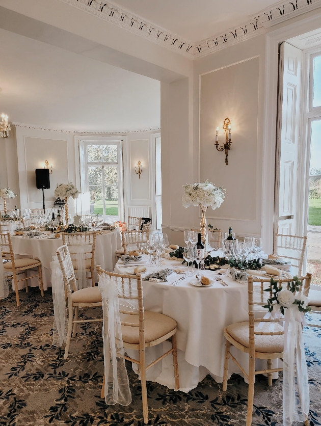 wedding reception table with gold candle stick, white flowers and green foliage. 