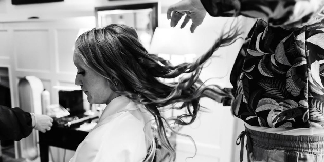 bride in dressing gown in chair having her hair done