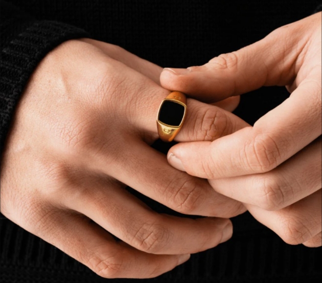 man wearing black and gold ring