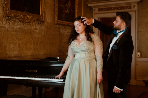 model in green dress having hair wiped from face by model in suit